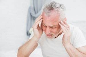 Lesiones comunes tratadas por médicos especializados en lesiones personales: hombre mayor masajeando la cabeza como si tuviera dolor
